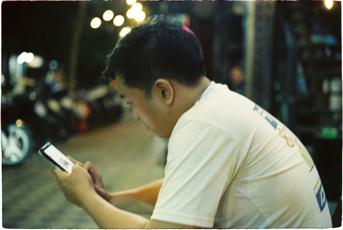 晚上在街頭低頭看手機的男子
