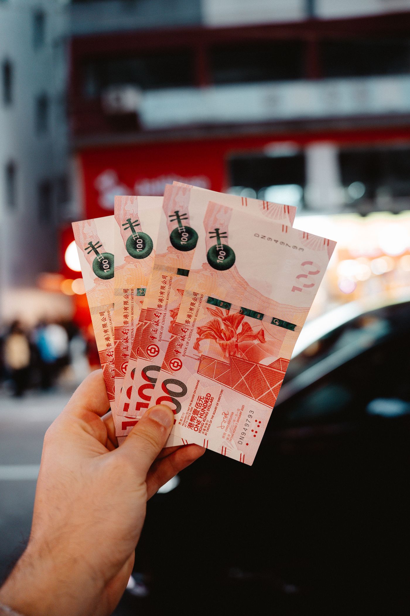 手持港元紙幣，背景為香港街道