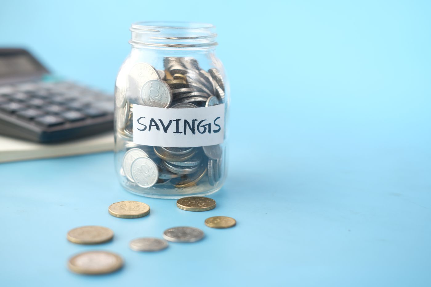 貼有 Savings 標籤的硬幣玻璃瓶旁放着計算機