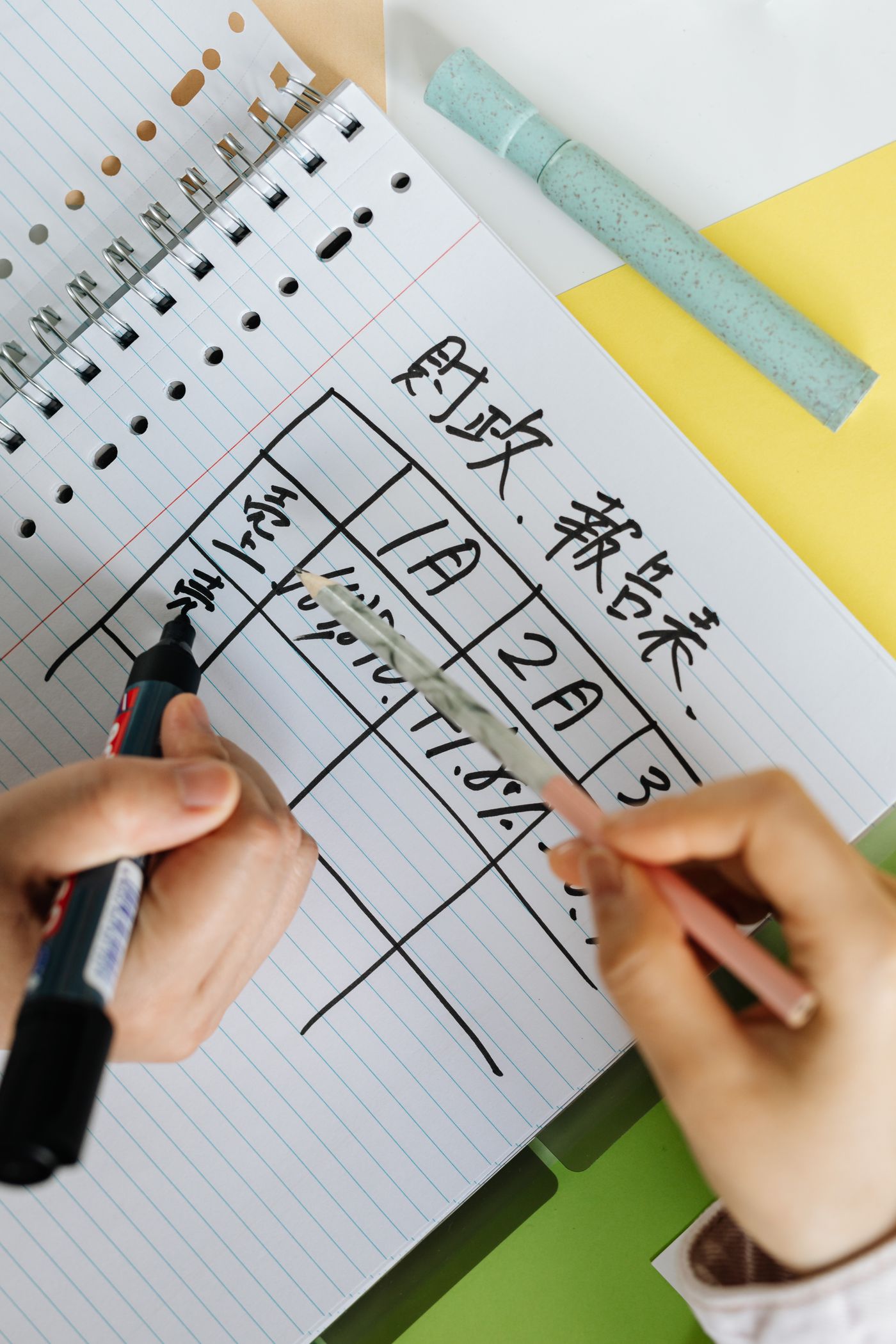 手持筆在記事本上整理年度收支計劃